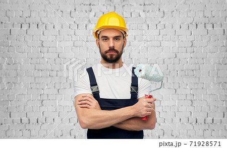 male builder with paint roller over brick wall 71928571