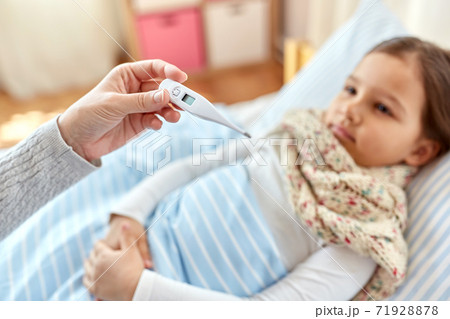 mother measuring temperature of sick daughter 71928878