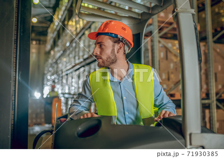 Young bearded worker in yellow vest looking concentrated 71930385