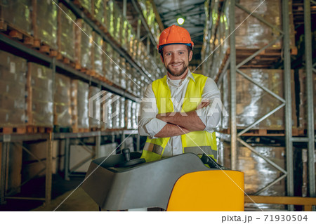 Warehouse worker in orange helmet looking contented 71930504