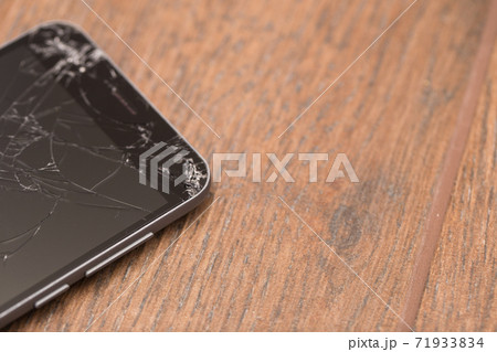 A broken phone is on the floor. Smartphone cracked screen closeup. A broken phone is on the floor. Smartphone cracked screen closeup. 71933834