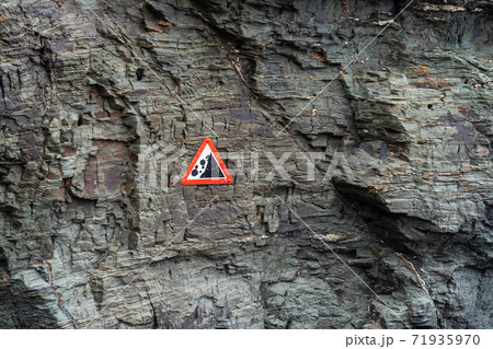 Sign warning of falling rocks from a cliff face due to erosion 71935970