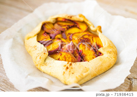 Peach galette on parchment, rustic wooden background. Homemade tart open pie with fresh fruits 71936415