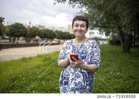 Happy middle-aged woman smiling speaks by phone on park natural background. 71938008