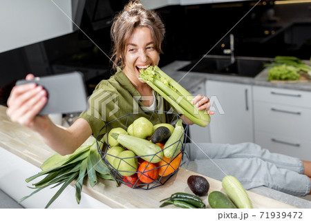 Woman with healthy food and phone on the kitchen at home Woman with healthy food and phone on the kitchen at home 71939472