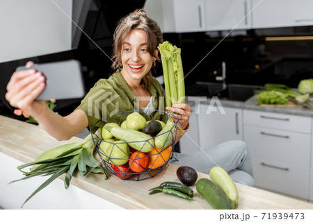 Woman with healthy food and phone on the kitchen at home 71939473