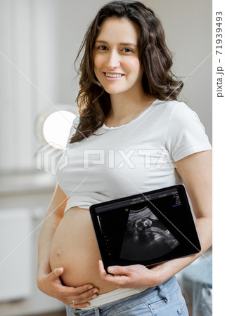 Pregnant woman with ultrasound scan of her baby Pregnant woman with ultrasound scan of her baby 71939493
