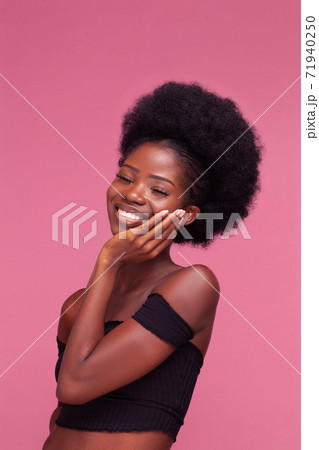 Charming Afro American girl smiling touching her chick after spa or face treatment. Beauty girl spa treatment isolated on pink background. Beauty concept. 71940250