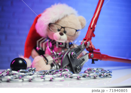 a toy bear wearing leather belts and a Santa Claus hat in the New year Christmas is chained and handcuffed an accessory for BDSM games next to a bolt cutter a toy bear wearing leather belts and a Santa Claus hat in the New year Christmas is chained and handcuffed an accessory for BDSM games next to a bolt cutter 71940805