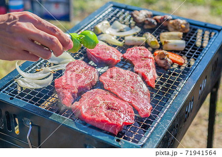 屋外のオープングリルで牛肉を網焼きしている様子 71941564
