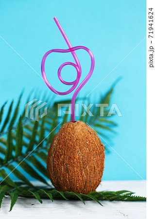 A coconut with straw on blue background. Summer and trave concept. copy space A coconut with straw on blue background. Summer and trave concept. copy space 71941624