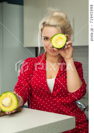 blonde vegan holding avocado in the kitchen blonde vegan holding avocado in the kitchen 71945998