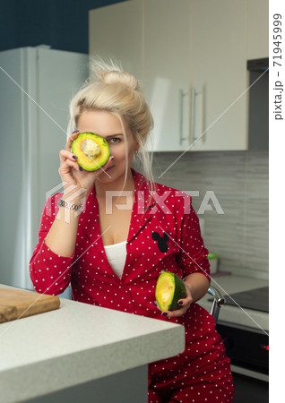 blonde vegan holding avocado in the kitchen 71945999
