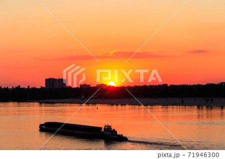 Tugboat pushing a heavy long barge on the river Dnieper at sunset Tugboat pushing a heavy long barge on the river Dnieper at sunset 71946300