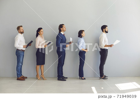 Young candidates for vacancy or job seekers standing in line with resumes and waiting for interview 71949039