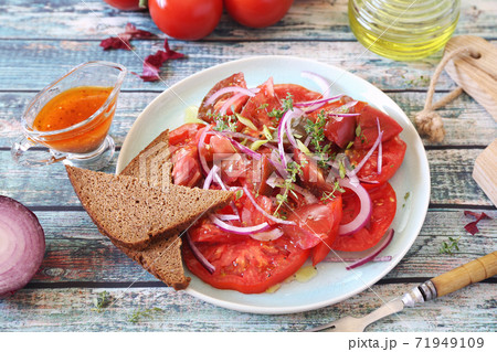 Tomato salad with red onion and spicy sauce of different varieties of tomatoes, two slices of rye bread 71949109