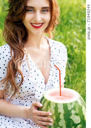 Woman holds watermelon on grass. Woman holds watermelon on grass. 71949244