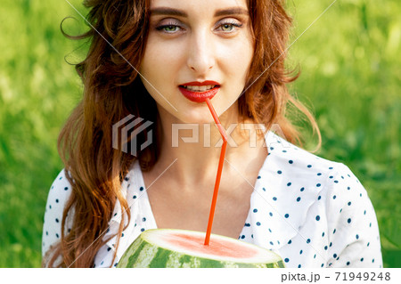 Woman holds watermelon on grass. Woman holds watermelon on grass. 71949248