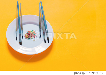 Brushes and rice painted in different colors on a plate, yellow background Brushes and rice painted in different colors on a plate, yellow background 71949337