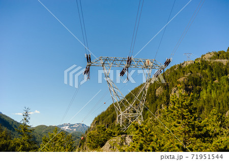 Power lines and tower passing through mountains. 71951544