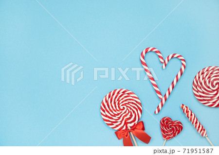 Christmas red striped candy canes and lollipops on blue background. Merry Christmas sweets and Happy New Year concept. Flatlay, copy space 71951587