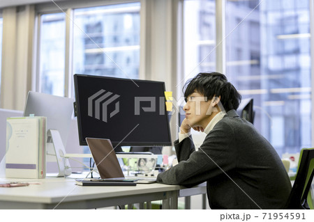 パソコンの前で考え込む若い男性 71954591