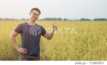 Asian young man standing in a field of rice. 71960807