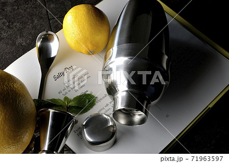 グレープフルーツやレモンやミントを使ってカクテルの本を見ながらシェーカーでカクテルを作る 71963597