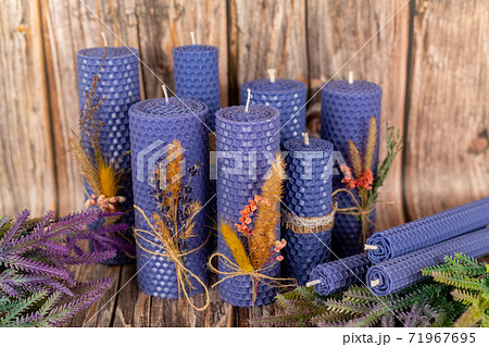 Lilac honey candles handmade from natural wax on a background of wooden boards. Elements from natural materials. Christmas or New Year's composition. Photo for postcards. Lilac honey candles handmade from natural wax on a background of wooden boards. Elements from natural materials. Christmas or New Year's composition. Photo for postcards. 71967695