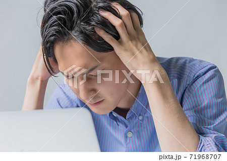 仕事で失敗をして頭を抱える若い男性 71968707
