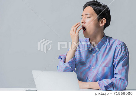 仕事に疲れてあくびをする若い男性 71969000