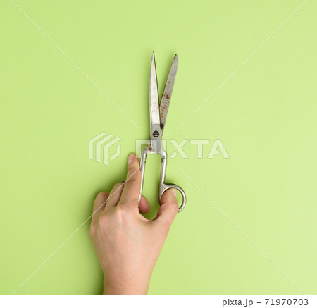 hand holds metal scissors on green background hand holds metal scissors on green background 71970703