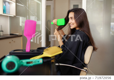 Female customer combs hair in hairdressing salon 71972056