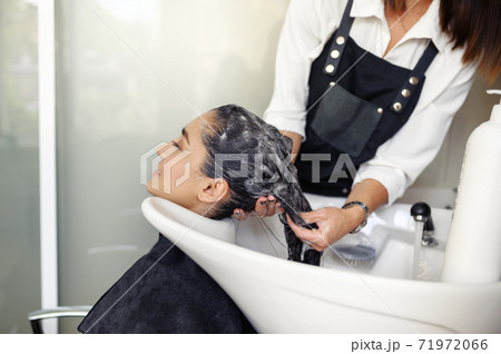 Hairdresser washes woman's hair, side view 71972066