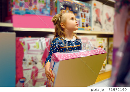 Little girl holds box with doll in toy store Little girl holds box with doll in toy store 71972140