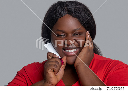 Young dark-skinned woman in red clothes holding a tube with face foundation 71972365