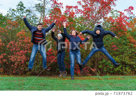 family jumping in autumn city park, happy people together, parents and children, beautiful nature with colorful leaves 71973762
