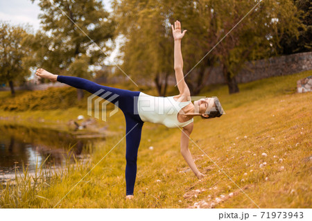 Young attractive yogi woman practicing yoga, doing Utthita Trikonasana exercise, extended triangle pose 71973943