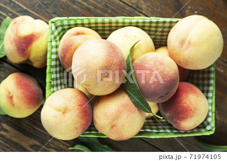 Fresh harvest of peaches in a basket on a wooden rustic table. 71974105