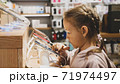 Little child girl using new smartphone on counter in an electronics store. 71974497