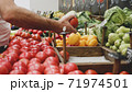 Close-up hands of grocery worker is arranging vegetables on store shelves 71974501