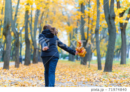 a girl running through the park and enjoys autumn, beautiful nature with yellow leaves 71974840