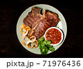 Roasted meat on a plate. Restaurant food. Grilled meat steak with sauce. Wooden background. 71976436