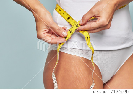 Woman measuring her waist with a tape measure 71976495