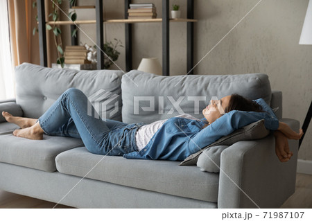 Exhausted woman relax on sofa at home daydreaming 71987107