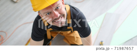 Smiling carpenter helmet sawing laminate flooring 71987657