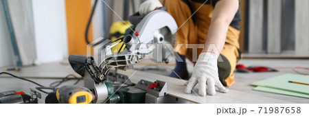 Repairman sawing laminate panels floor in room Repairman sawing laminate panels floor in room 71987658