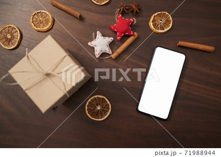 flat lay with smarthone and christmas decorations on walnut table 71988944