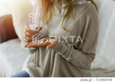 Close-up woman holding pills time to take medications, cure for headache. Medicine concept during self isolation and Coronavirus pandemic 71990449