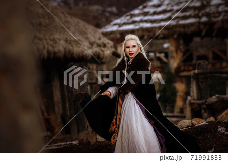 Beautiful blonde Viking dressed in a black cloak against the backdrop of the castle 71991833